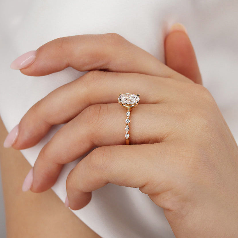 Close-up of ASTER oval cut lab diamond yellow gold scatter ring on model’s hand, side angle view