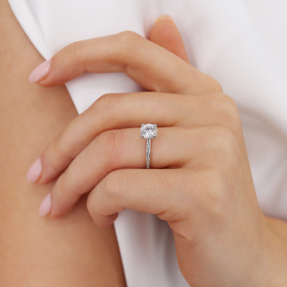 Close-up of LILY 18k white gold channel set engagement ring with round lab diamond, worn on hand