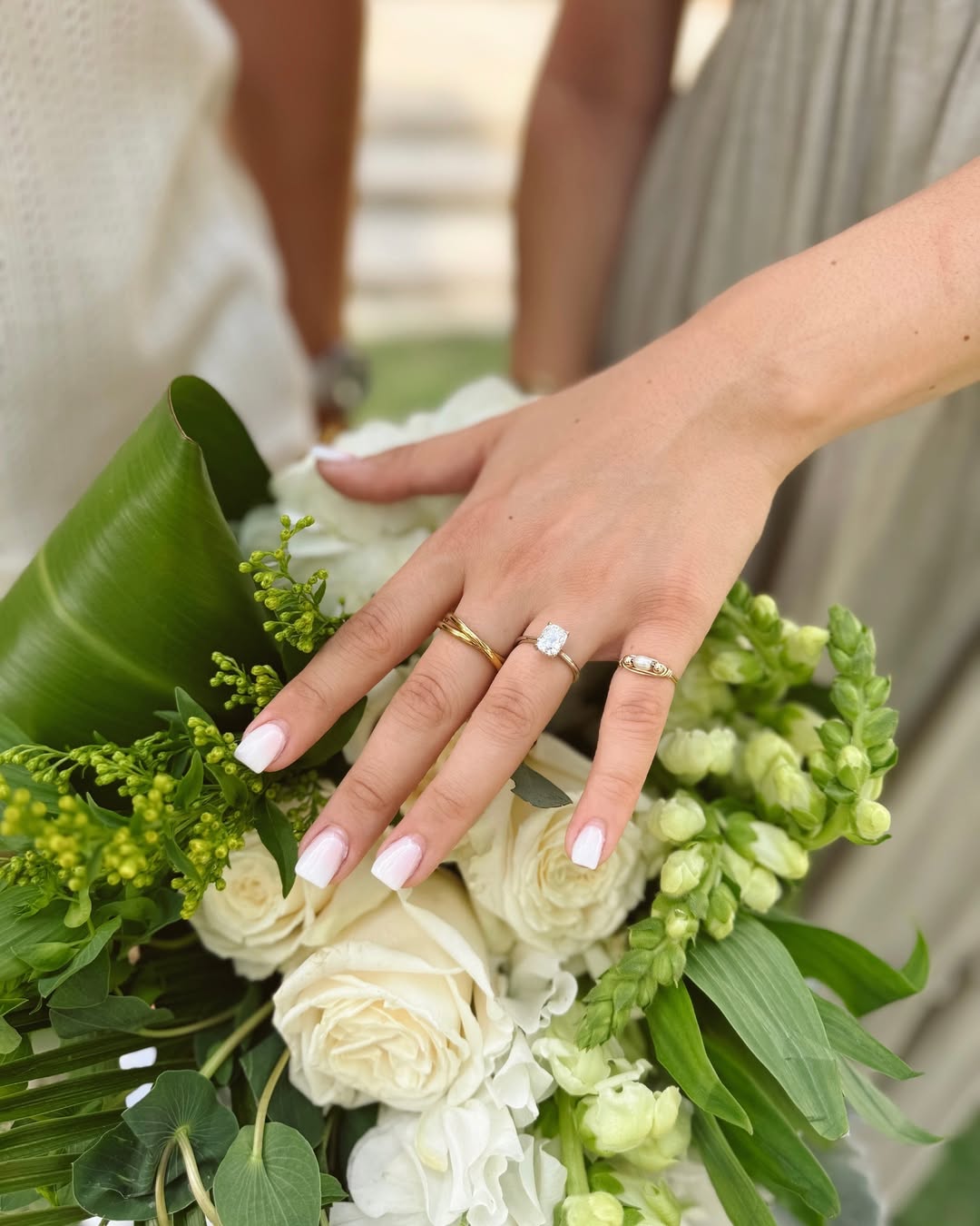 Bridal hand with diamond ring resting gently on a bouquet of white roses—perfect for wedding themes.