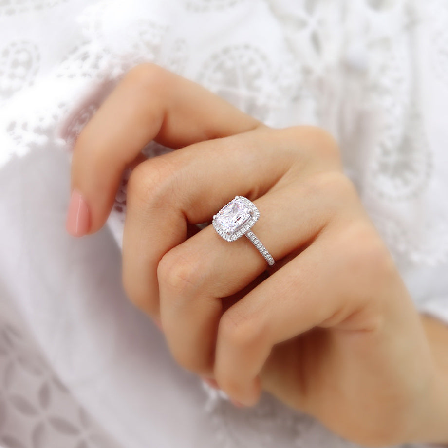 Elongated cushion lab diamond halo engagement ring in platinum, lifestyle hand view