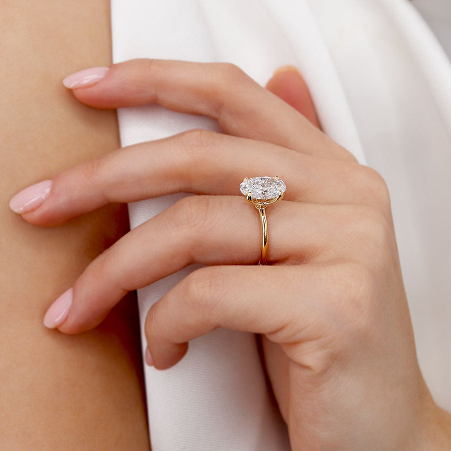 Lifestyle image of oval lab diamond rose gold engagement ring on model’s finger