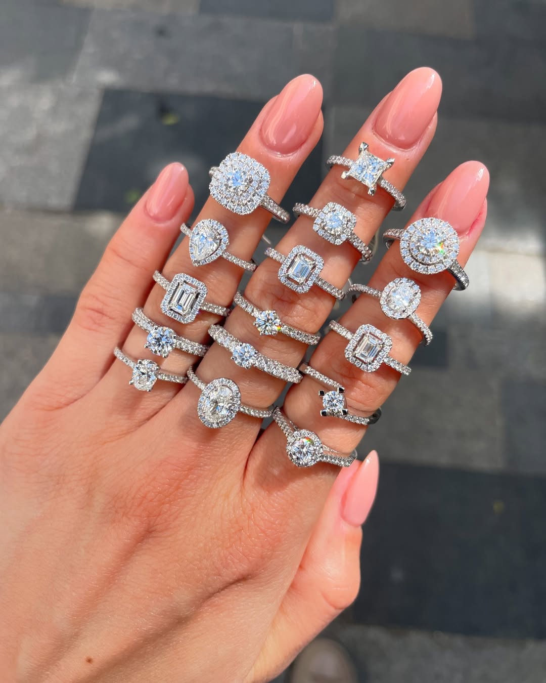 Red-manicured hand with multiple rings stacked, featuring gold and diamond bands.