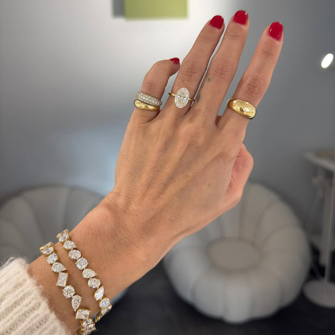 Hand with red nails featuring an eye-catching marquise diamond ring stack.