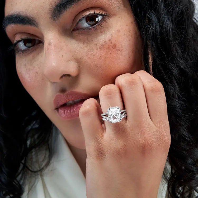 Woman wearing radiant cut lab diamond halo engagement ring, close-up view