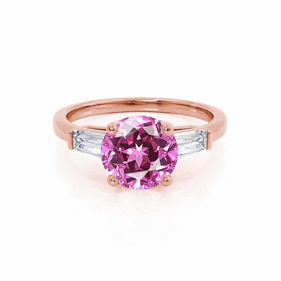 Front view showcasing the romantic round-cut pink sapphire and baguette diamond trilogy in a polished rose gold band.