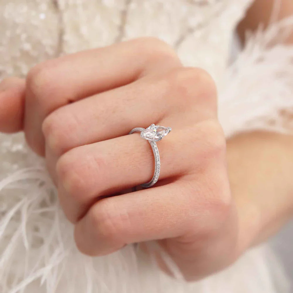Woman wearing marquise cut lab diamond solitaire engagement ring in 18k rose gold, close-up hand view