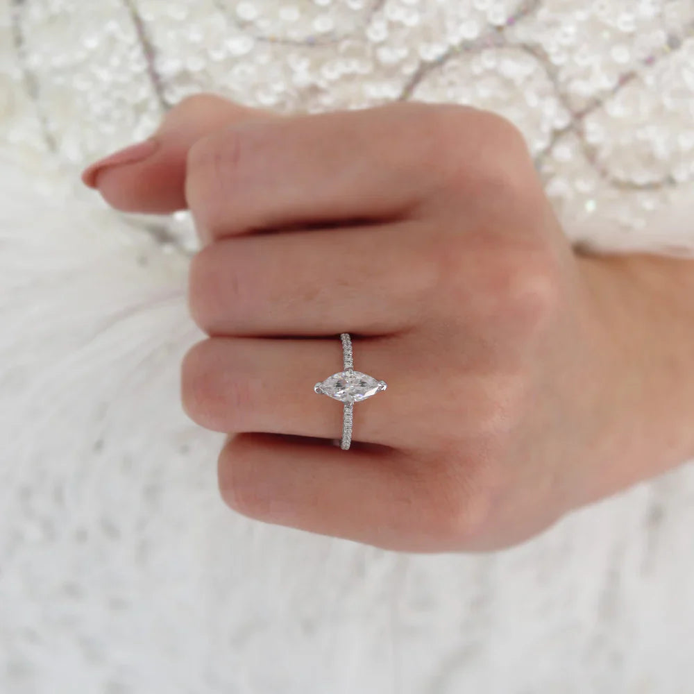 Woman wearing marquise cut lab diamond solitaire engagement ring in 18k yellow gold, close-up hand view