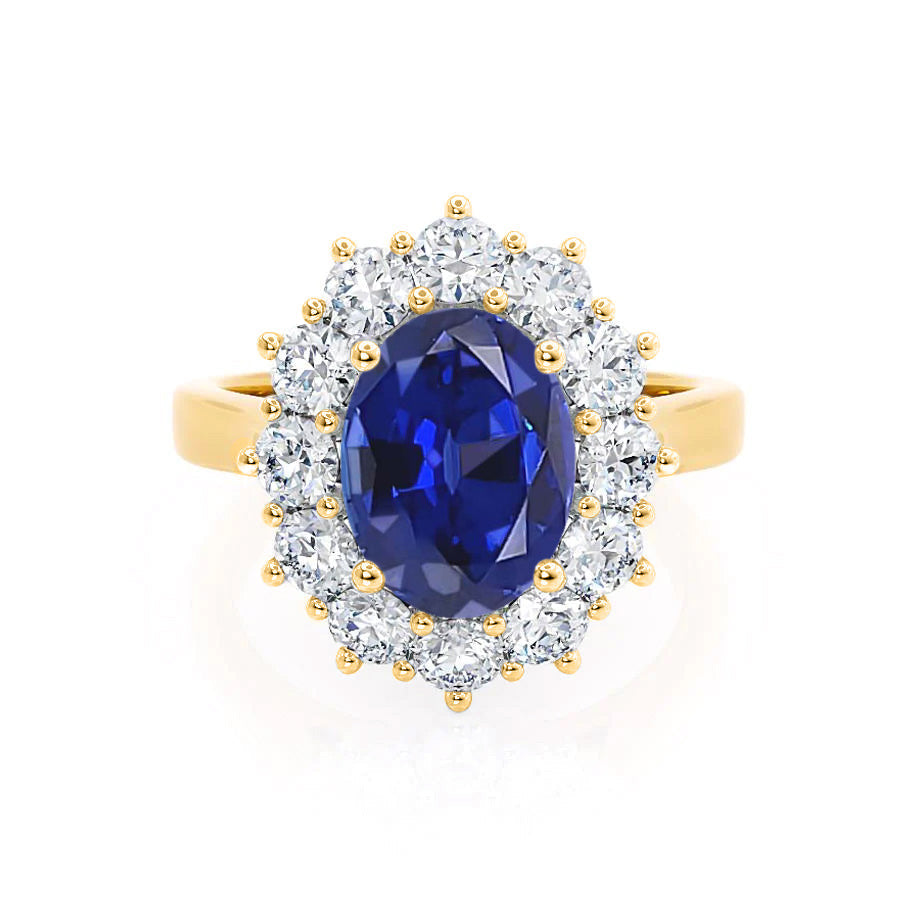 Front view – A brilliant oval-cut blue sapphire surrounded by a radiant diamond halo in vibrant 18k yellow gold.