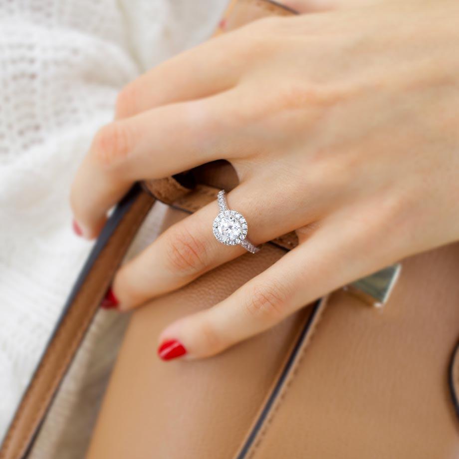 Model wearing Daisy platinum halo ring with round lab diamond while holding a bag