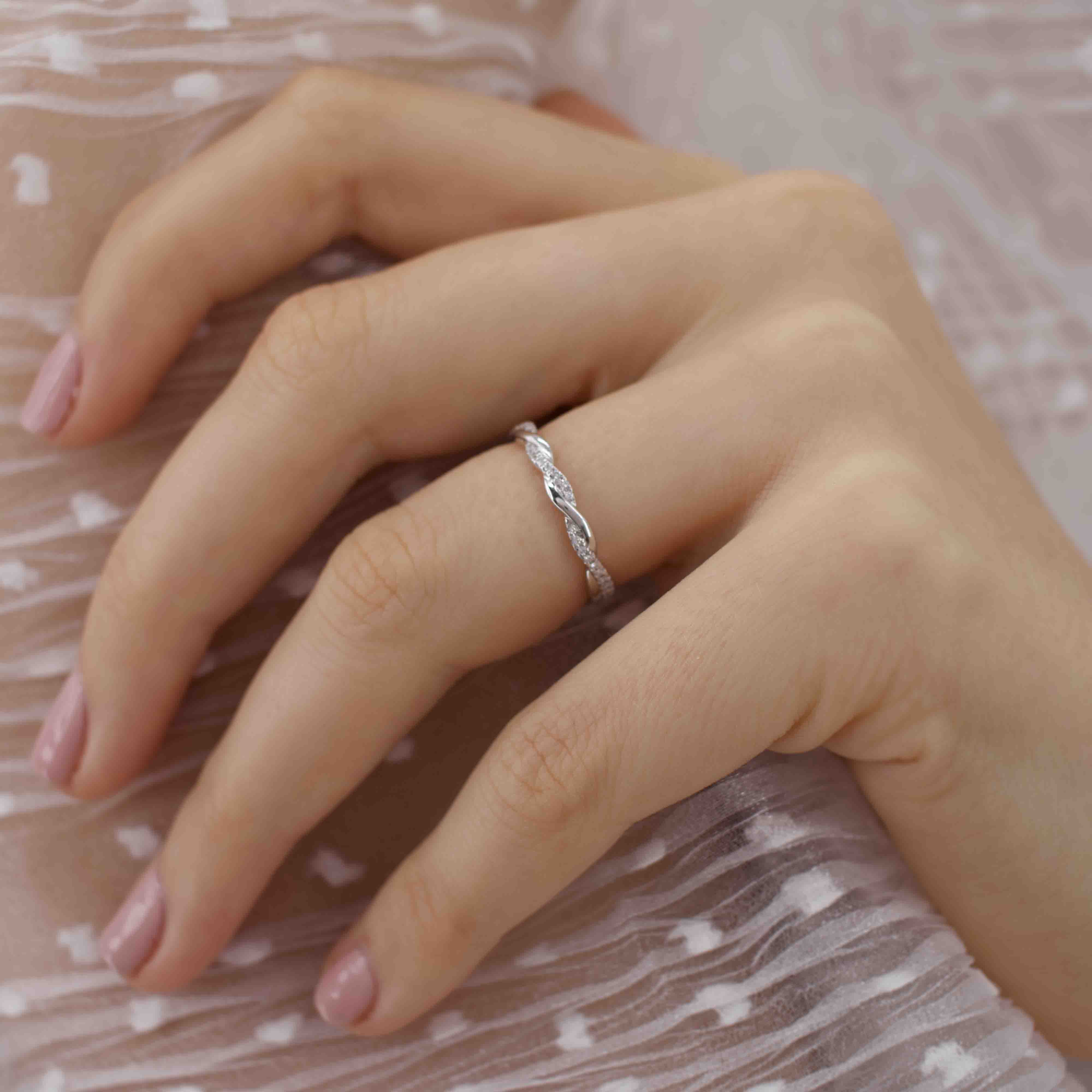 Model hand wearing the twisted leaf ring, styled on blush-toned fabric for elegance.