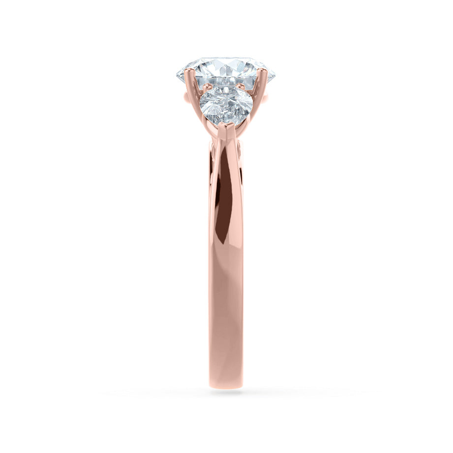 Side view of oval lab diamond trilogy ring in 18k rose gold with pear cut side diamonds