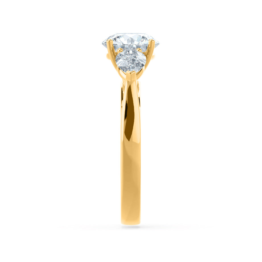 Profile view of oval cut lab diamond with pear side diamonds trilogy engagement ring in 18k yellow gold