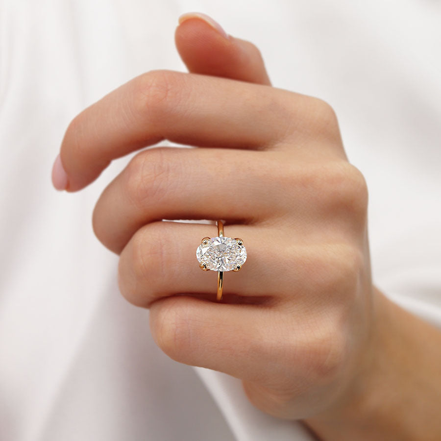 Close-up of 18k rose gold oval lab diamond ring on woman's hand